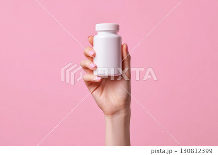 Hand holding a white supplement bottle. Medicine mockup. Blank label vitamin template. Natural organic bio Pills jar. Pink studio color background. Clear packaging. Trendy Product presentation 130812399
