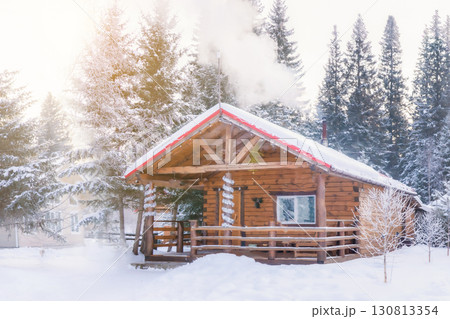 Russian wooden bathhouse in a snowy clearing in winter. Smoke is coming out of the bathroom chimney. Russian wooden bathhouse in a snowy clearing in winter. Smoke is coming out of the bathroom chimney. 130813354