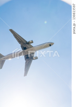 まぶしい太陽と青空の下を通過していく旅客機　ロンドン郊外のヒースロー空港近くにて 130813597