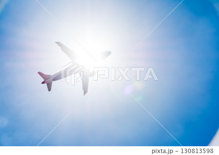 まぶしい太陽と青空の下を通過していく旅客機　ロンドン郊外のヒースロー空港近くにて 130813598