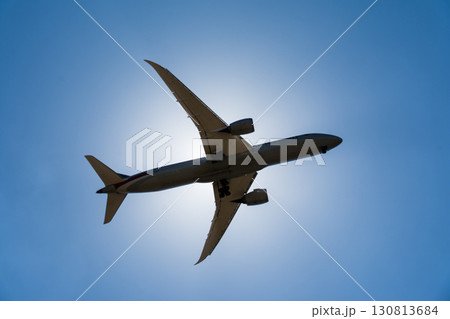 まぶしい太陽と青空の下を通過していく旅客機　ロンドン郊外のヒースロー空港近くにて 130813684