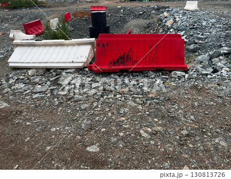 Red and white construction barriers are placed on rocky terrain, surrounded by gravel and debris, illustrating an industrial site with a rugged environment and construction elements Red and white construction barriers are placed on rocky terrain, surrounded by gravel and debris, illustrating an industrial site with a rugged environment and construction elements 130813726