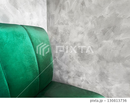 Elegant green velvet chair or sofa positioned against a textured gray wall, modern interior design elements and creating a stylish atmosphere for contemporary spaces, copy space Elegant green velvet chair or sofa positioned against a textured gray wall, modern interior design elements and creating a stylish atmosphere for contemporary spaces, copy space 130813736