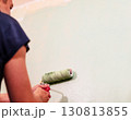 man is painting a wall with a green roller, showcasing the creative process of home improvement and interior design in a bright environment, copy space 130813855