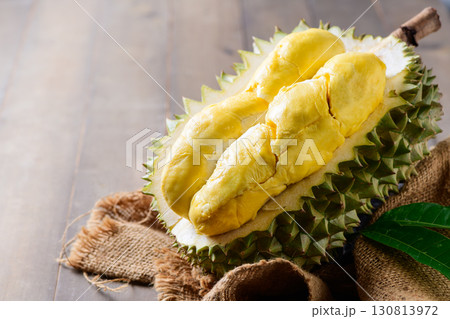 Ripe durian fruit or Durio zibethinus with yellow creamy pulp exposed on wood background. king of fruits Ripe durian fruit or Durio zibethinus with yellow creamy pulp exposed on wood background. king of fruits 130813972