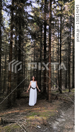 Woman wearing white dress walking in coniferous forest in vsechlapy, czechia Trail of the Knight Woman wearing white dress walking in coniferous forest in vsechlapy, czechia Trail of the Knight 130814045