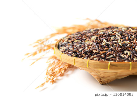 Close-up of organic mixed rice grains in a traditional bamboo basket with dried rice ears isolated on white background. Healthy natural food, agriculture product, and Asian cuisine ingredient concept. 130814093