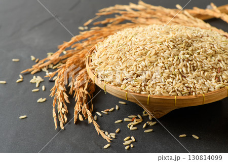Brown Rice in Bamboo Basket with Rice Ears on Black Background Organic Healthy Grain 130814099