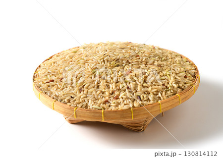 traditional woven basket filled with uncooked brown rice grains isolated. 130814112
