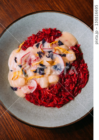 Spanish cuisine. Rice food. Tomato paella with stewed scallops in creamy sauce. Tasty launch decorated with dried herb spice on plate. 130816695