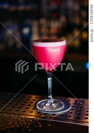 Cocktail glass. Alcoholic drink. Pink liquor served on metal pub counter. Beverage in elegance glassware presentation on restaurant. Cocktail glass. Alcoholic drink. Pink liquor served on metal pub counter. Beverage in elegance glassware presentation on restaurant. 130816698
