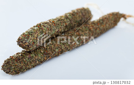 Spiced spanish fuet sausages in herbs on white background Spiced spanish fuet sausages in herbs on white background 130817032
