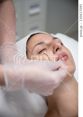 Beautician applying cosmetic treatment on female face with cotton swab in beauty salon Beautician applying cosmetic treatment on female face with cotton swab in beauty salon 130817095