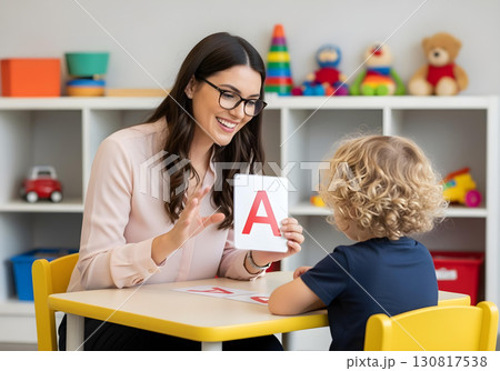 Autistic child boy in speech therapy learning alphabet with therapist holding card for communication skills and autism inclusion awareness 130817538