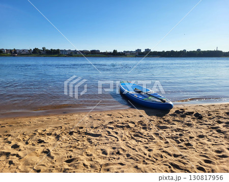 The inflatable SUP board lies on the edge of the sand and the river The inflatable SUP board lies on the edge of the sand and the river 130817956