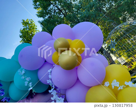 On a sunny day, festive inflatable blue, yellow, and lilac balloons in a children's park 130817958