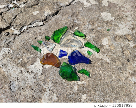 Shards of green, blue, white, and brown glass lie on the road. 130817959