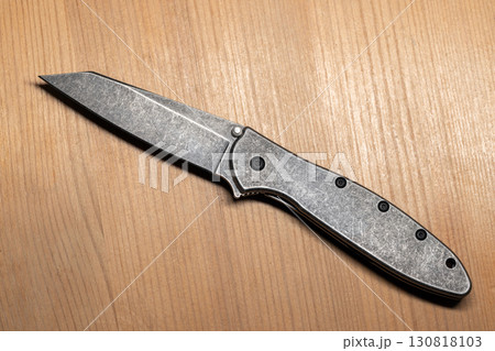 Detailed view of a modern gray steel folding knife with a sleek design Detailed view of a modern gray steel folding knife with a sleek design 130818103
