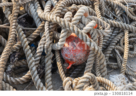 Ropes intricately tangled around a weathered red buoy, close up photo Ropes intricately tangled around a weathered red buoy, close up photo 130818114