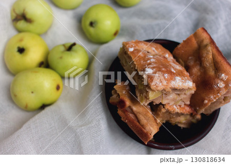 Apple pie with powdered sugar with green apples. Autumn dessert. Homemade dessert. Apple pie with cinnamon and fresh apple fruits. Country still life. Sweet dessert. Homely vibes.  130818634