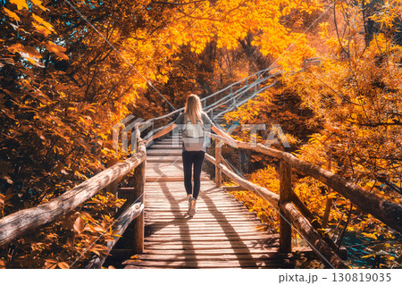 Woman with backpack walking on wooden path. Waterfalls in autumn Woman with backpack walking on wooden path. Waterfalls in autumn 130819035