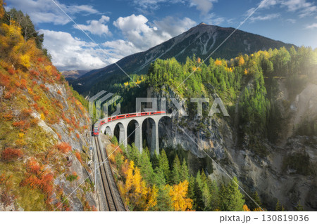 Aerial view of modern red train on Landwasser viaduct 130819036