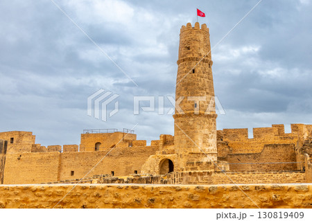 Inner yards and watch tower with tunisian flag on the top of Ribat of Monastir under cloudy skies, Monastir, Monastir Governorate, Tunisia 130819409