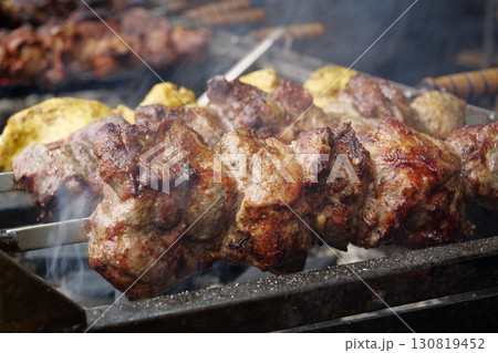 Appetizing hot kebabs. Shish kebabs broil on barbecue. Different meat are cooked 130819452