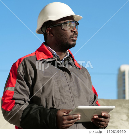 African american worker with tablet computer stands at construction site 130819460