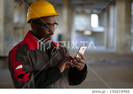 African american workman with smartphone at construction site 130819466