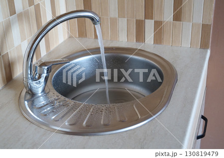 Water pours in a strong stream from the tap in kitchen 130819479