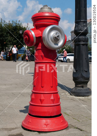 Red fire hydrant stands on a city street 130819504