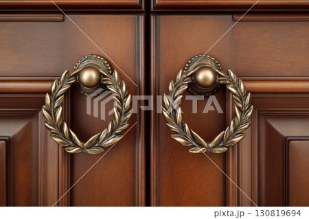 Elegant Wooden Door Handles with Intricate Wreath Shape Design to Enhance Your Home Decor. Stylishly crafted wooden cabinet doors embellished with ornate brass handles. Antique Door Knob. Metalwork 130819694