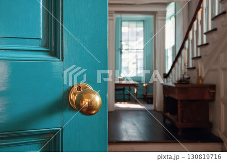 Blue color door and silver latch. Colorful front door, doorknob and keyhole, white wall. Traditional handle and lock. Metal hardware. Close-up vibrant colored front door detail. Modern house exterior. 130819716