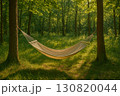 Hammock suspended between trees in a serene forest setting with dappled sunlight filtering through leaves 130820044