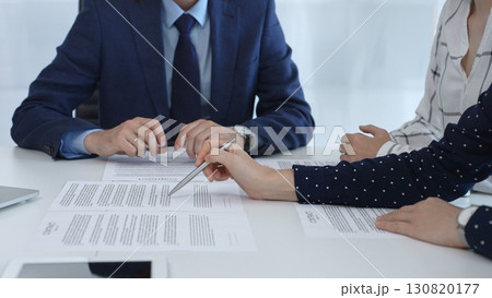 Business people reviewing contract terms and conditions during a meeting, gesturing with hands, engaging in negotiations and legal discussions Business people reviewing contract terms and conditions during a meeting, gesturing with hands, engaging in negotiations and legal discussions 130820177