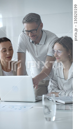 Business people team collaborating and analyzing data on a laptop during an office meeting, uniting efforts to reach shared objectives and drive successful outcomes together 130820199