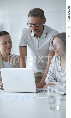 Business people collaborating and analyzing data on a laptop during an office meeting Business people collaborating and analyzing data on a laptop during an office meeting 130820201