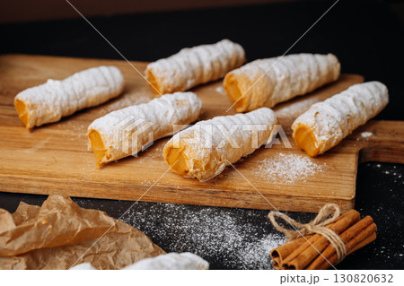 Caramel cream filled pastry rolls dusted with powdered sugar on parchment paper 130820632