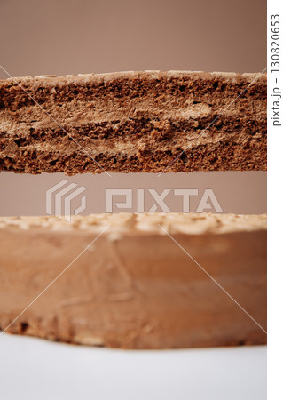Slice of chocolate cake with creamy layers, levitating above whole dessert on stand Slice of chocolate cake with creamy layers, levitating above whole dessert on stand 130820653