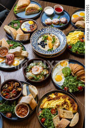 Delicious variety of gourmet breakfast dishes served on wooden table in cozy restaurant Delicious variety of gourmet breakfast dishes served on wooden table in cozy restaurant 130820991