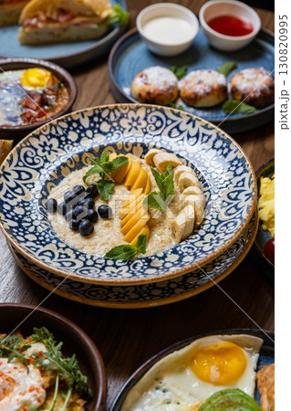 Healthy oatmeal porridge with banana, peach, blueberries and mint in patterned bowl Healthy oatmeal porridge with banana, peach, blueberries and mint in patterned bowl 130820995