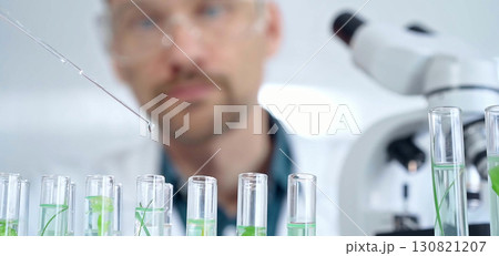 Man researcher with safety glasses is working with lab tubes using a pipette in laboratory, close-up of lab equipment. Science and medicine 130821207