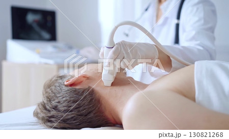 Doctor woman wearing white medical coat performing neck ultrasound exam on male patient. Medicine service concept 130821268