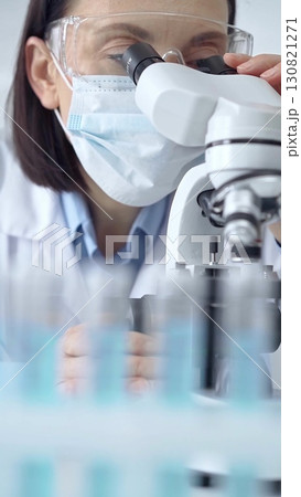 Female scientist using microscope in laboratory, portrait. Focus on a woman in lab goggles analyzing samples in a scientific setting Female scientist using microscope in laboratory, portrait. Focus on a woman in lab goggles analyzing samples in a scientific setting 130821271