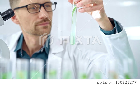 Scientist examining lab tube with a green fluid. Microbiology and science concept Scientist examining lab tube with a green fluid. Microbiology and science concept 130821277