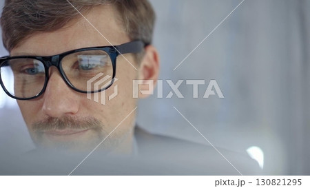 Businessman with glasses looking intently obscured partially by a translucent surface of laptop. Business people concept 130821295