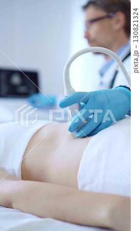 Doctor man wearing a blue protective gloves using an ultrasound machine on a female patient examining internal organs. Medicine concept 130821324