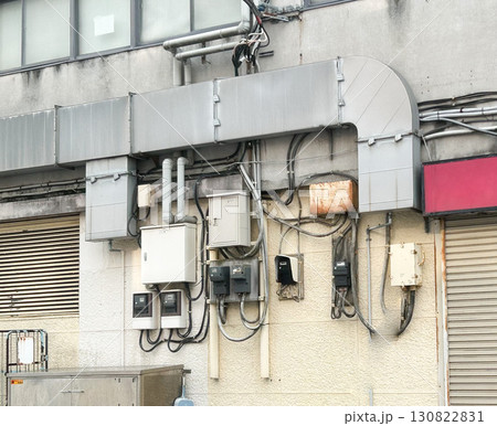 建物の外壁の電気メーター、分電盤、配線電気と排気ダクト 建物の外壁の電気メーター、分電盤、配線電気と排気ダクト 130822831