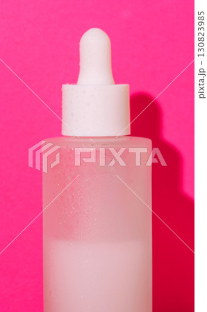 Frosted glass serum bottle with condensation on pink background, skincare concept Frosted glass serum bottle with condensation on pink background, skincare concept 130823985